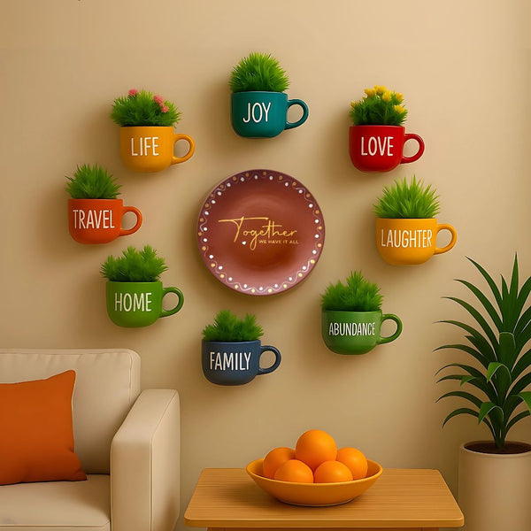 Decorative wall art with text on mugs and a plate, featuring plants and a bowl of oranges on a table.