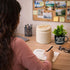 Person writing in a journal at a desk with a 'Gratitude' mug and decorative items.