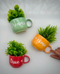 A set of three ceramic wall planters in red, blue, and yellow colors with green plant sprouts. Each planter has a different motivational word written on it: 'DREAMS', 'TRUE', and 'COME'.